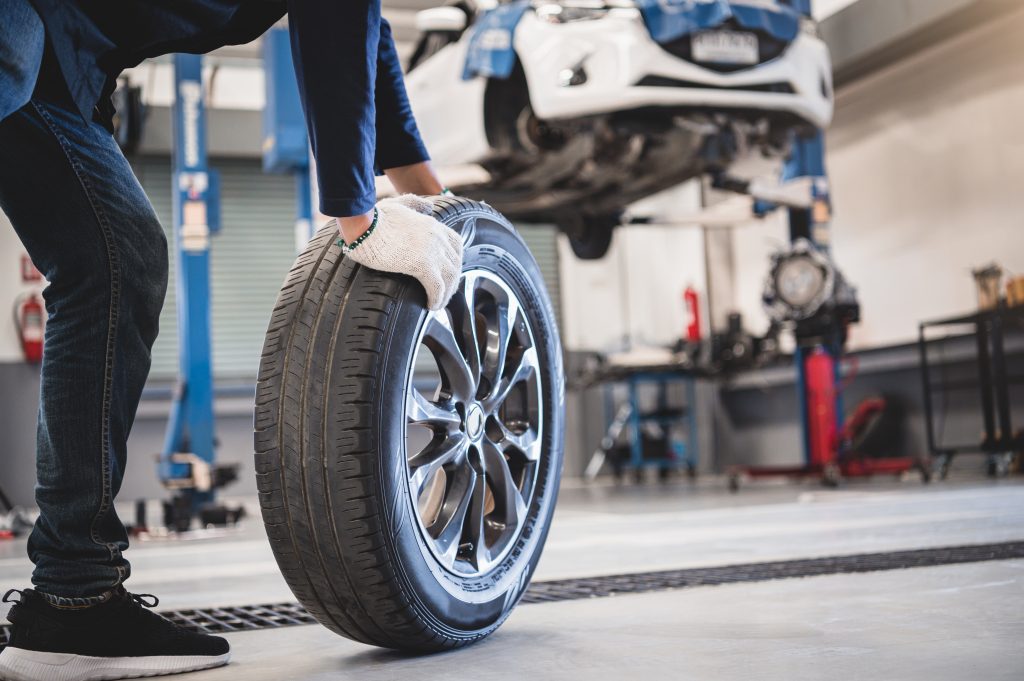 Un mécanicien tient et roule un pneu dans un garage de réparation.